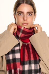A model styled in a charcoal and red cashmere scarf, representing the brand's global appeal.