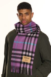 A premium navy and green tartan scarf draped over a luxury travel trunk, symbolising global reach and heritage.
