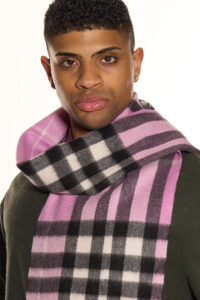 A folded red and grey tartan cashmere scarf on a wooden surface.